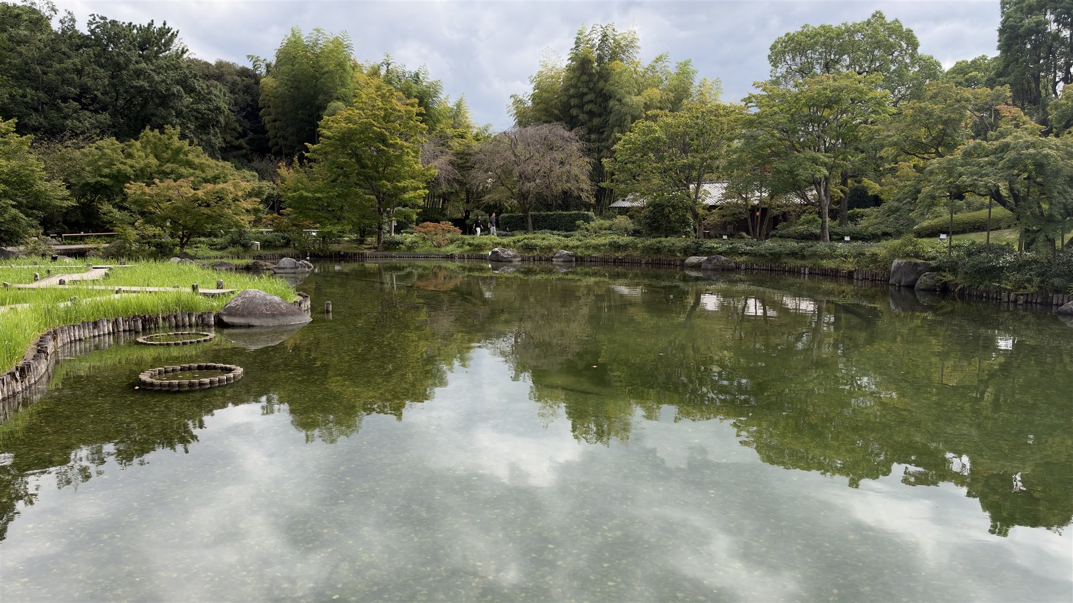 石と水面と雲の反射が重なる日本庭園